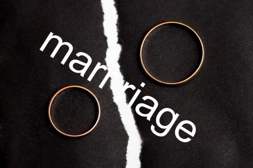 Wedding rings on different halves of a torn sheet of paper. Broken word marriage