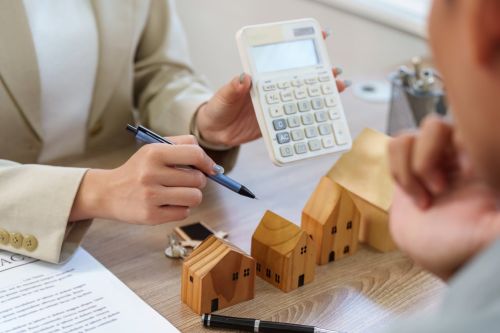 A real estate agent uses a calculator to discuss financial aspects of property investment with a client, ensuring informed decisions.