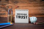 Irrevocable trust. Cardboard notepad on wooden texture table.